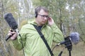 The man with Shotgun Condenser Microphone and headphones is recording the sounds of nature.