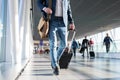 Man with shoulder bag and hand luggage walking in airport terminal