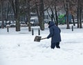 Man with a shovel clears snow outdoor. Worker during snow removal in winter city, street cleaning Royalty Free Stock Photo