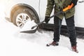 Man is shovelling snow near the car. Winter shoveling. Removing snow after blizzard