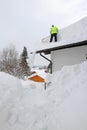 A man shovels dangerously heavy snow from a house roof Royalty Free Stock Photo