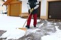 A man shovels snow in front of the garages