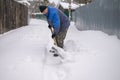 man shovels snow in the yard in winter. Clearing a road in a country village or village Royalty Free Stock Photo