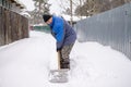 man shovels snow in the yard in winter. Clearing a road in a country village or village Royalty Free Stock Photo