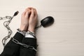 Man showing hands chained with computer mouse cable at white wooden table, top view. Internet addiction Royalty Free Stock Photo