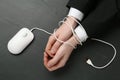 Man showing hands tied with computer mouse cable at black table, top view. Internet addiction Royalty Free Stock Photo