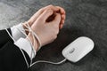 Man showing hands tied with computer mouse cable at grey table, closeup. internet addiction Royalty Free Stock Photo