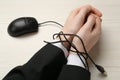 Man showing hands tied with computer mouse cable at white wooden table, closeup. Internet addiction Royalty Free Stock Photo