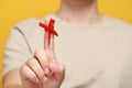 Man showing index finger with red tied bow as reminder against orange background, focus on hand Royalty Free Stock Photo