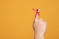 Man showing index finger with red tied bow as reminder on orange background, closeup. Space for text Royalty Free Stock Photo