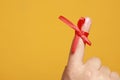 Man showing index finger with red tied bow as reminder on orange background, closeup. Space for text Royalty Free Stock Photo