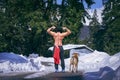 Man showing muscles with dog along side standing together gazing at the mountain
