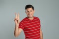 Man showing number two with his hand on grey background Royalty Free Stock Photo