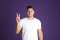 Man showing number two with his hand on purple background Royalty Free Stock Photo