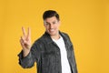 Man showing number two with his hand on yellow background Royalty Free Stock Photo