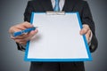 Man is showing and offering blank white paper in clipboard with pen Royalty Free Stock Photo