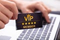 Man Showing VIP Member Card While Using Laptop