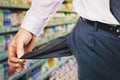 Man shows an empty pocket on the background of the store. Concept of the lack of money for purchases