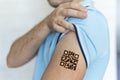 Man shows his shoulder with a qr code, a confirmation of the vaccination against the covid 19 coronavirus. Temporary tattoo Royalty Free Stock Photo