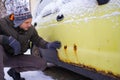 A man shows rust on a car door from winter reagents. Close-up, selective focus on rust and hand.
