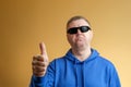 A man shows a thumbs up gesture. Portrait of a man in a blue hoodie and sunglasses Royalty Free Stock Photo