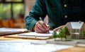 Man signing paper and home model with pen, home loan paperwork image