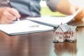 Man signing real estate contract papers with small model home in front Royalty Free Stock Photo