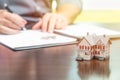 Man signing real estate contract papers with small model home in front Royalty Free Stock Photo