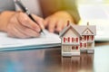 Man signing real estate contract papers with small model home in front Royalty Free Stock Photo