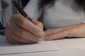 A man signs documents with a pen, making a signature, sitting at a table in the light. Royalty Free Stock Photo