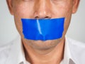 Man is silenced with adhesive red tape across his mouth sealed to prevent him from speaking. Freedom Concept Royalty Free Stock Photo