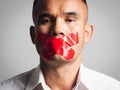 Man is silenced with adhesive red tape across his mouth sealed to prevent him from speaking. Freedom Concept Royalty Free Stock Photo