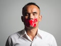 Man is silenced with adhesive red tape across his mouth sealed to prevent him from speaking. Freedom Concept