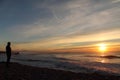 Man silhouette admiring atlantic ocean with breaking waves with mountain la rhune in the back in sunset, capbreton, france