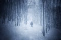 Man silhouette in dark surreal winter forest with fog and snow flakes