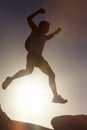 Man, silhouette and jump on rock at sunset with freedom, adventure and challenge on mountain or cliff. Climbing, hill Royalty Free Stock Photo