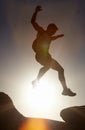 Man, silhouette and jump on rock at sunset with freedom, adventure and challenge on mountain or cliff. Climbing, hill