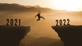 Man Silhouette Jumping from 2021 to 2022 Over Mountain. happy new year 2022. Sunset Mountains background. Young guy Jumps between Royalty Free Stock Photo