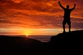 Man silhouette on the mountain top watching the sunrise over clouds and forest