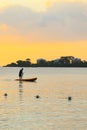 Man silhouette rowing standng on a boat at sunset time.