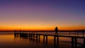 A man silhouette standing on wooden pier lonely at the sea with beautiful sunset. lsunset seascape at a wooden jetty. Royalty Free Stock Photo