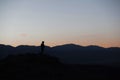 Man silhouette stay on sharp rock peak. Satisfy hiker enjoy view. Tall man on rocky cliff watching down to landscape. Royalty Free Stock Photo