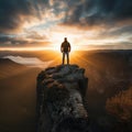 Man silhouette stay on sharp rock peak the view of sunset over an autumn forest in deep velly bellow. Enjoy the moment