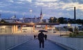 Man silhouette with umbrella on promenade walk Tallinn old town at horizon medieval tower ruffle night city lamp blurred on asph