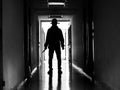 Man silhouette walking away with knife in the light of opening door in dark room, Threat Concept Royalty Free Stock Photo