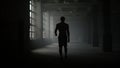 Man silhouette walking in dark corridor. Athlete taking break after workout Royalty Free Stock Photo