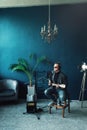 Man singer sitting on a stool in a headphones with a guitar recording a track in a home studio Royalty Free Stock Photo