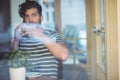 Man sipping coffee while talking on cellphone at cafe Royalty Free Stock Photo