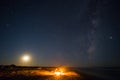 man sit on a chair near a fire on a sea coast under starry sky with milky way Royalty Free Stock Photo