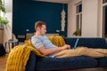 Man sit on couch with laptop on lap studying, relaxing, chilling, browsing Internet, checking news Royalty Free Stock Photo